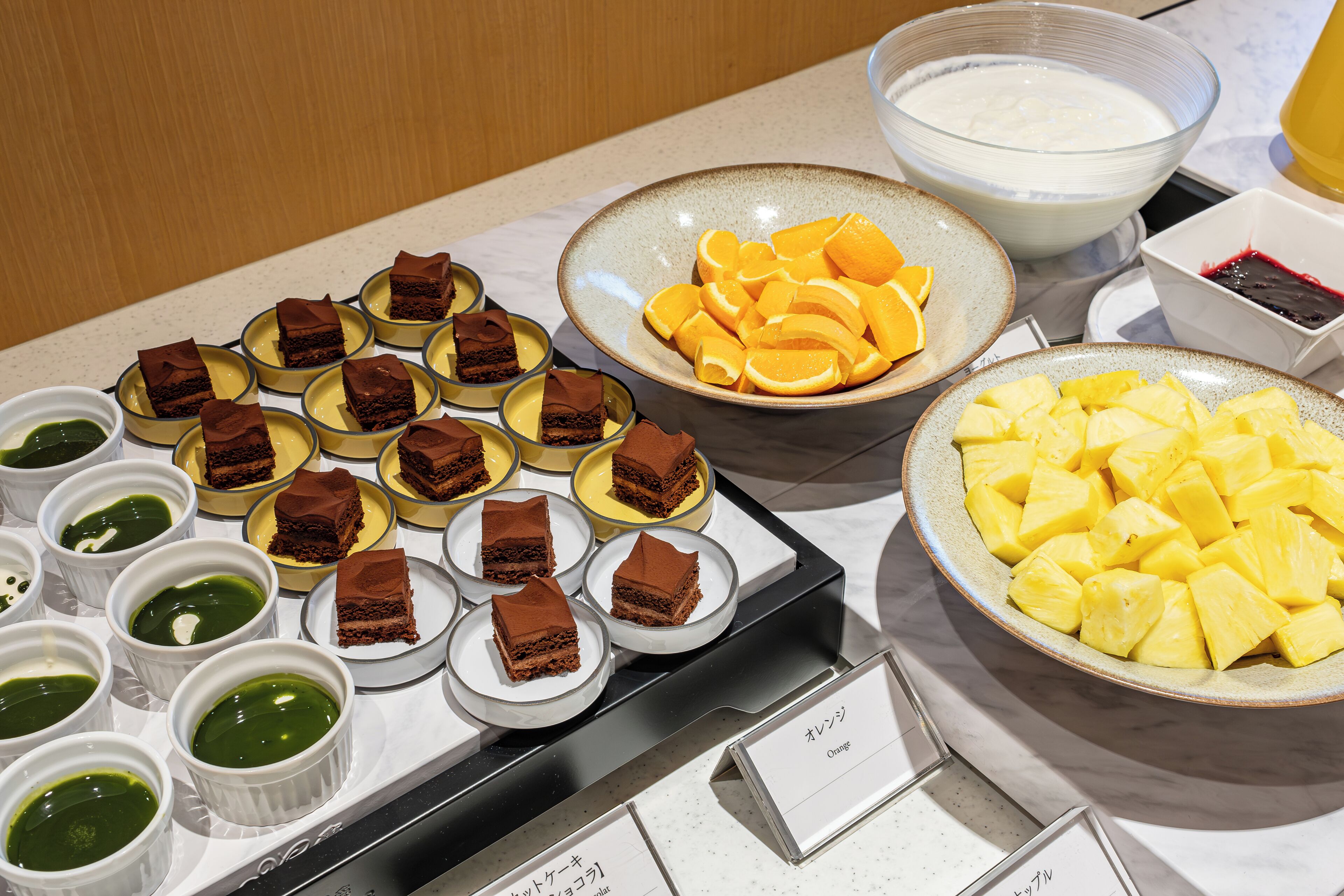 A buffet table with various desserts and fruits.