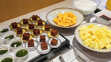 A buffet table with various desserts and fruits.