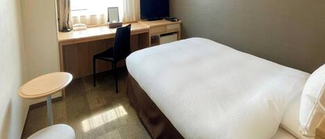 Una habitación de hotel con una cama, un escritorio con una computadora, una silla y una mesita.