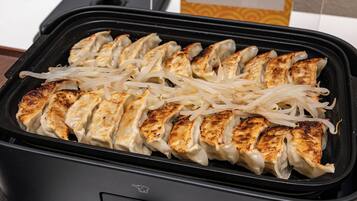 A food steamer with grilled chicken and noodles.