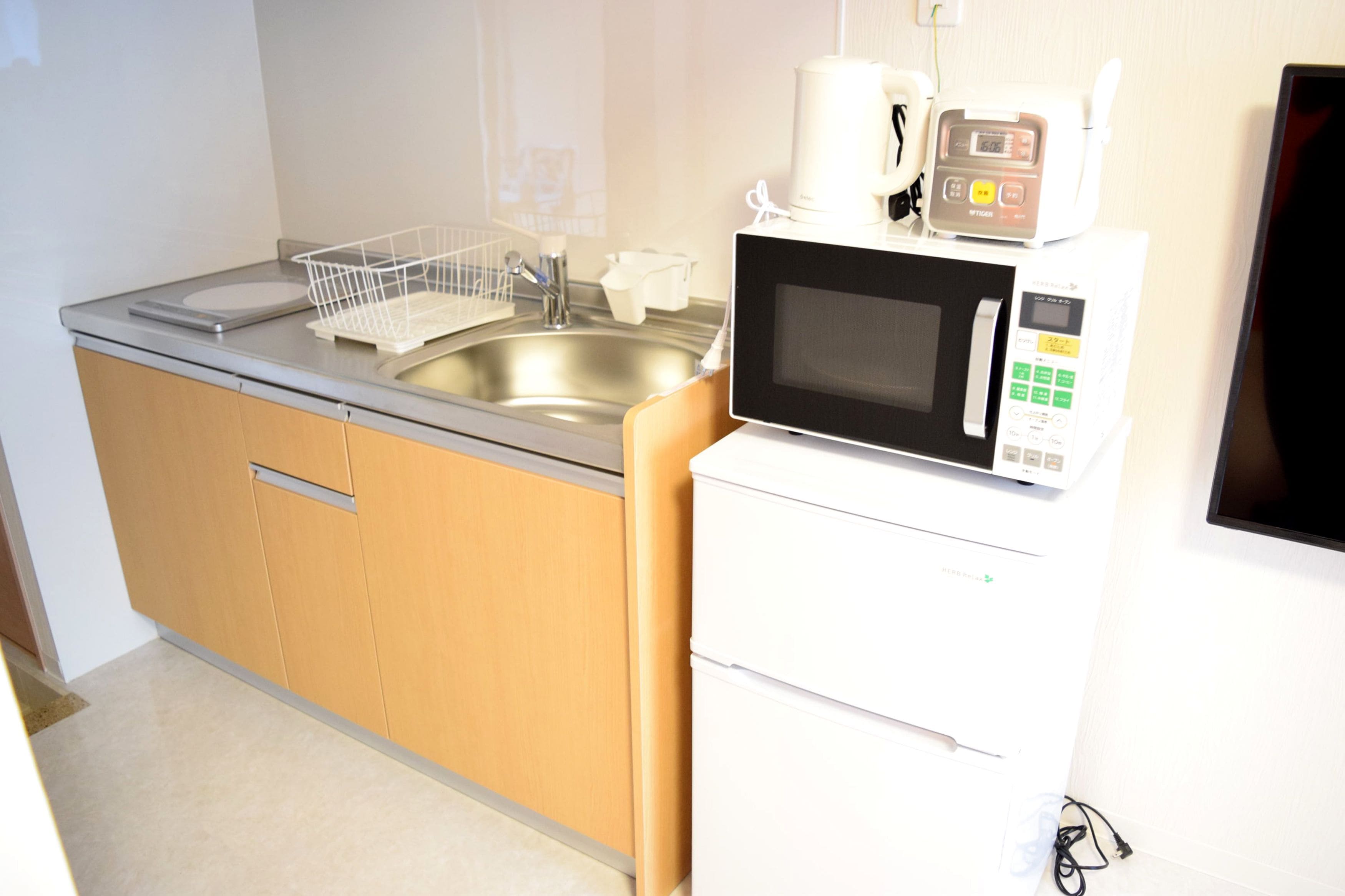 A compact kitchen with a stainless steel sink, a microwave, and a small refrigerator.