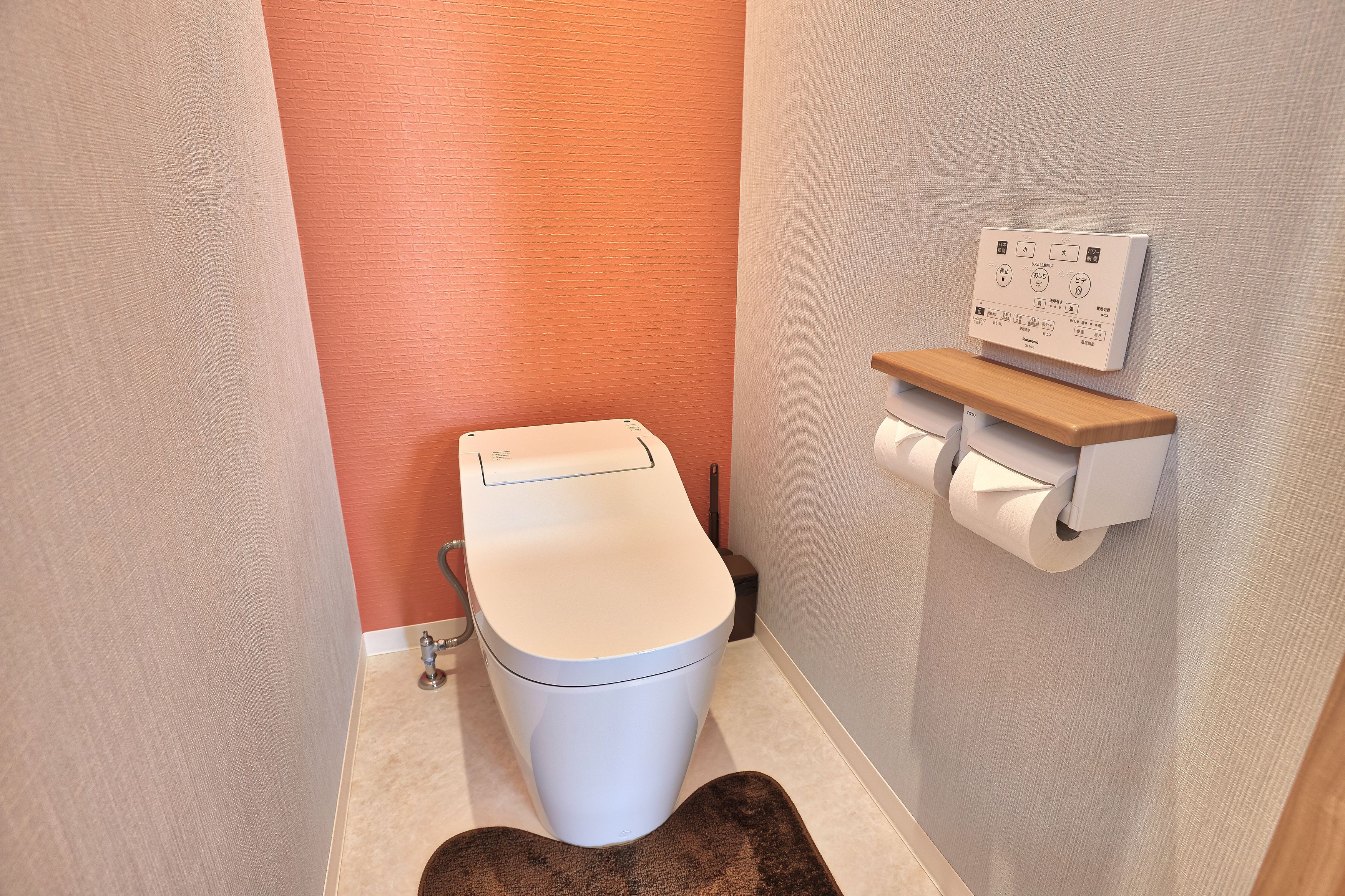 Ein modernes Badezimmer mit Toilette, einem Wand-Toilettenpapierhalter und Bedienfeld für die Spülung.
