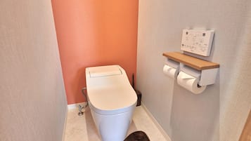 Ein modernes Badezimmer mit Toilette, einem Wand-Toilettenpapierhalter und Bedienfeld für die Spülung.