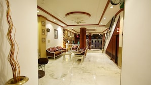 A hotel lobby with a marble floor, seating area with sofas and chairs, a reception desk, and a staircase leading to another floor. - Hotel Parkway Deluxe (New Delhi)