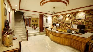 A hotel reception area with a curved reception desk, a staircase leading to another floor, and a check-in counter. - Hotel Parkway Deluxe (New Delhi)
