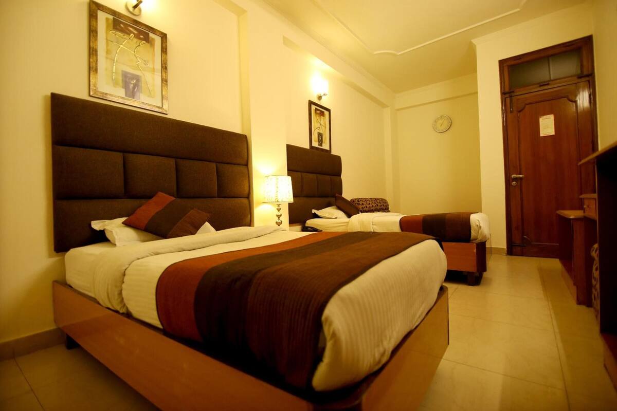 Una habitación de hotel con una cama grande, una cama más pequeña, un escritorio y un armario.