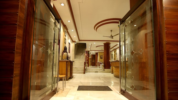 A hotel corridor with glass doors, a marble floor, and a staircase leading to the upper floors. - Hotel Parkway Deluxe (New Delhi)