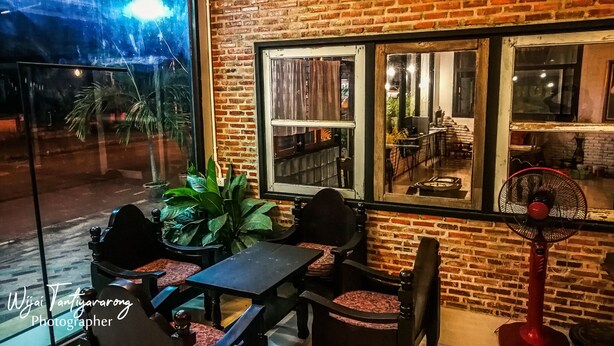 Un espacio al aire libre con paredes de ladrillo, un ventanal grande y un ventilador.