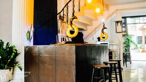 Una zona de bar con taburetes, una barra y lámparas colgantes.