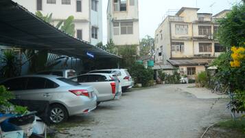 A row of parked cars in a residential area with buildings in the background.