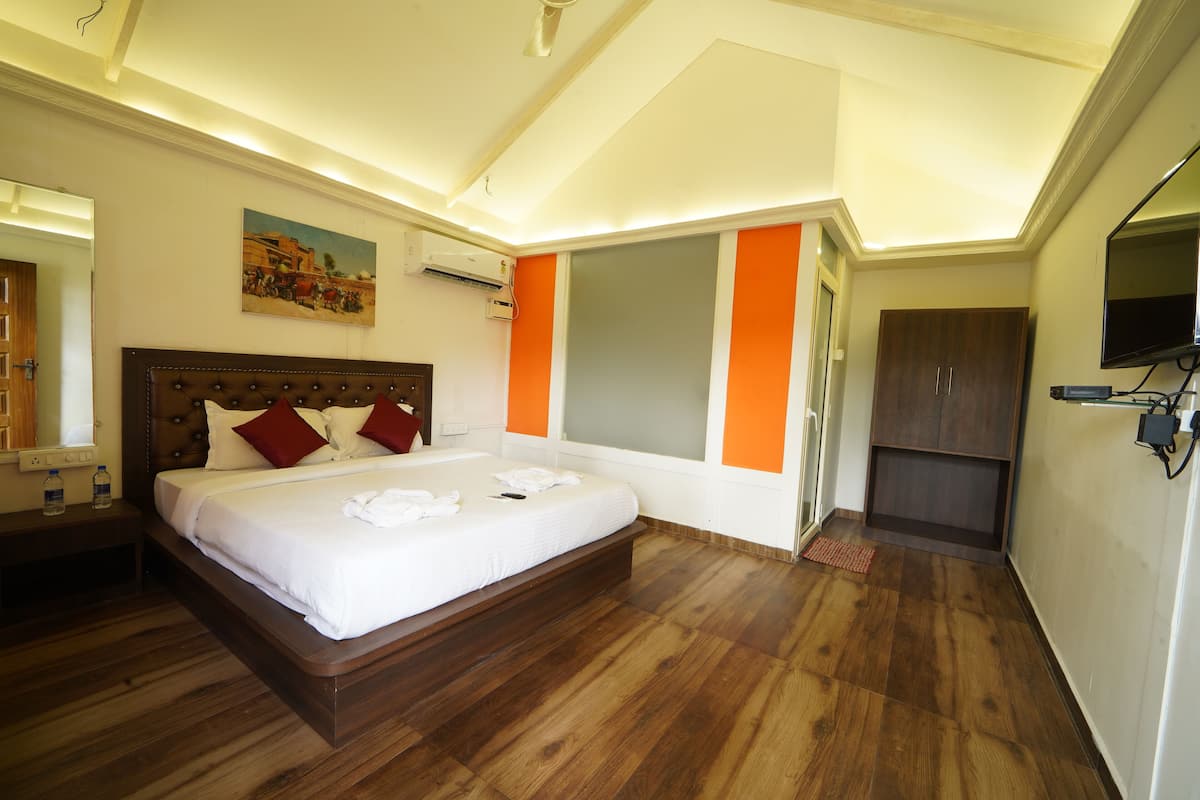 A hotel room with a large bed, a wooden floor, a painting on the wall, and a wardrobe.