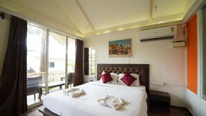 Habitación de hotel con una cama grande, un cuadro en la pared, un aire acondicionado y vistas al exterior.