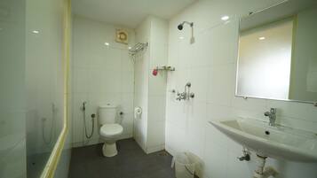 Une salle de bain équipée de toilettes, d’une douche, d’un lavabo et d’un miroir.