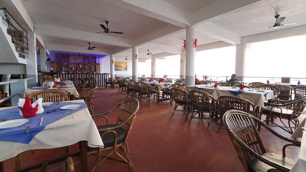 Un restaurant spacieux avec de hauts plafonds, de nombreuses tables et chaises, et de grandes fenêtres.