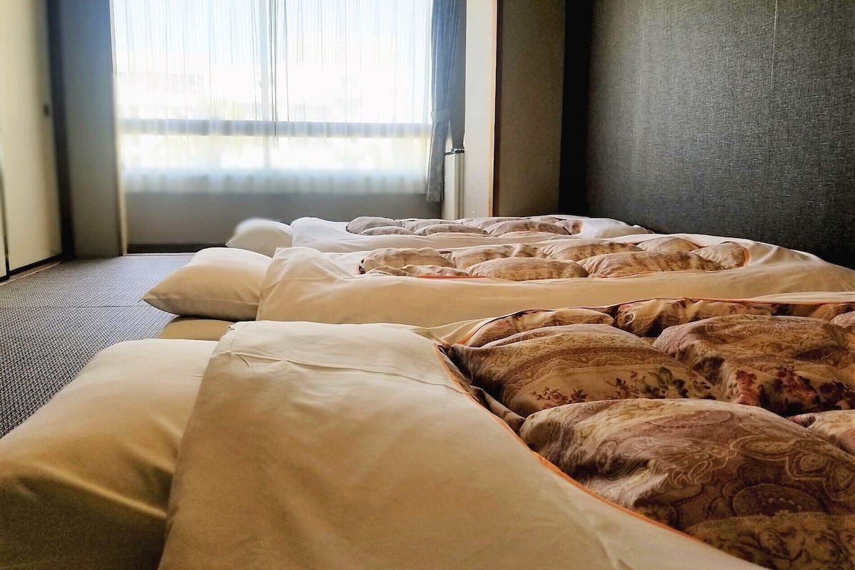 A hotel room with a bed, pillows, and a window with curtains.