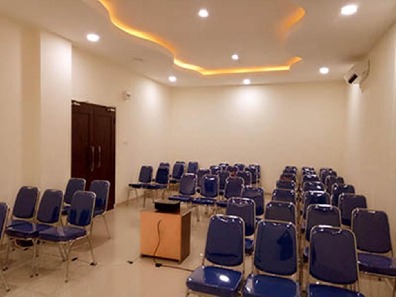 Une salle de conférence avec des rangées de chaises et un pupitre.
