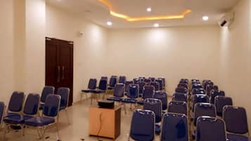 Une salle de conférence avec des rangées de chaises et un pupitre.
