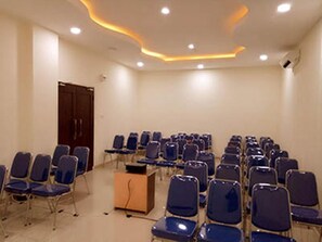 A conference room with rows of chairs and a podium. - Venia Hotel (Batam)