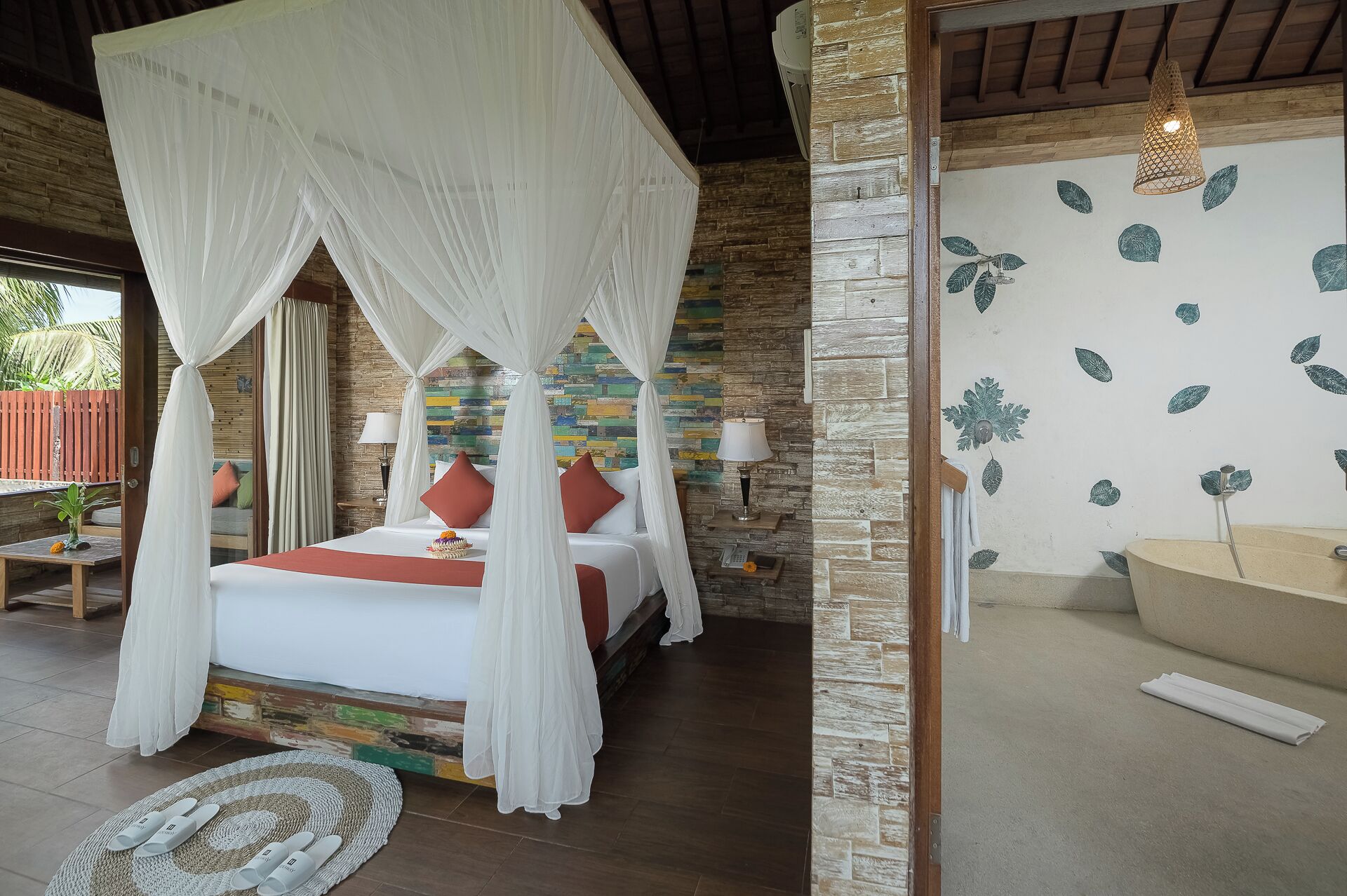 A bedroom with a four-poster bed, a stone wall, a patterned wall, and a hanging light fixture.