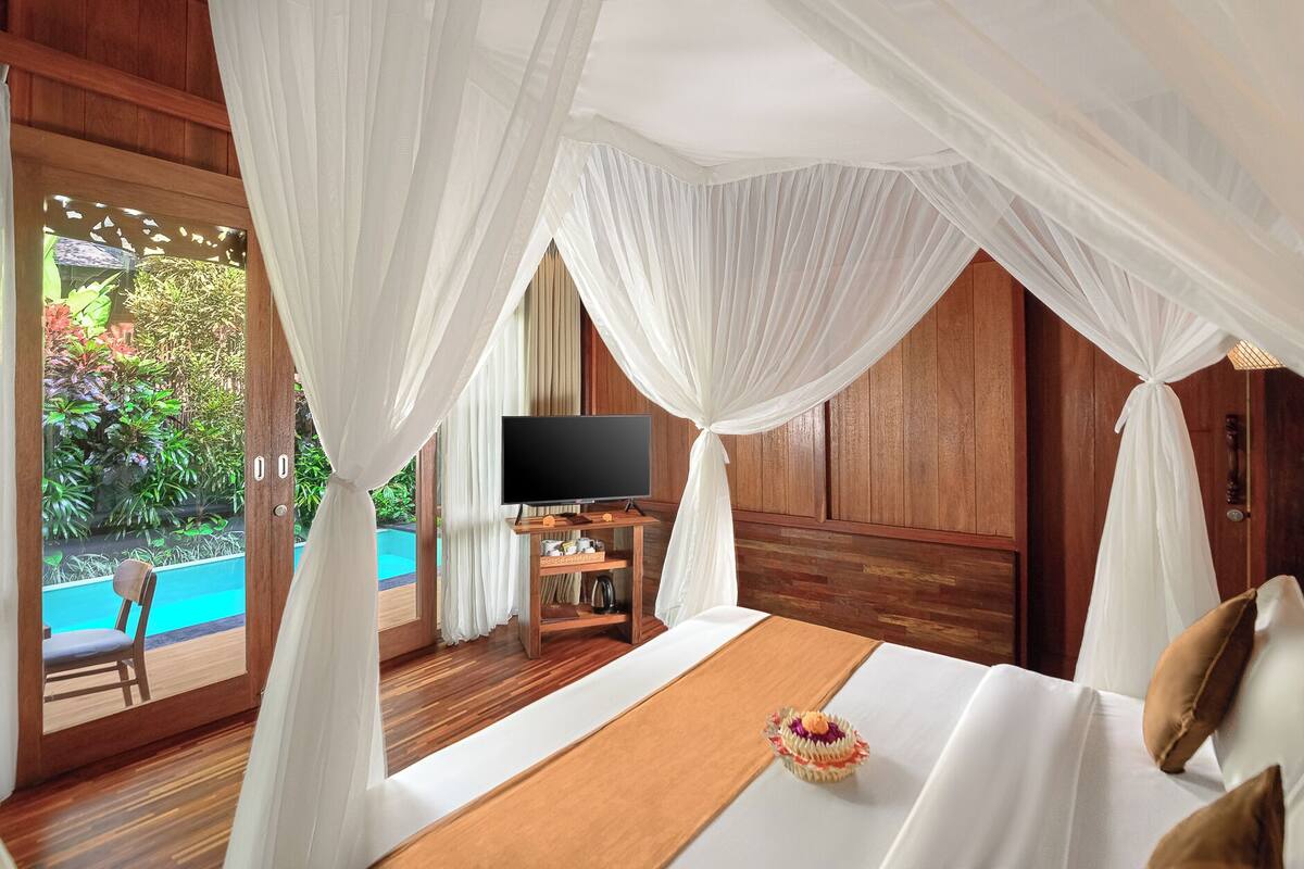 A bedroom with a bed, a TV, and a view of a swimming pool.