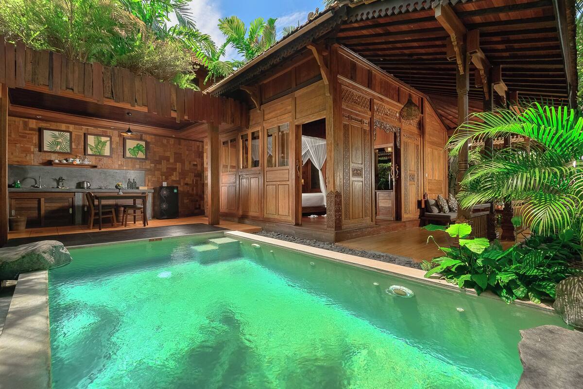 A poolside area with a wooden structure, a dining area, and a bedroom with a canopy bed.