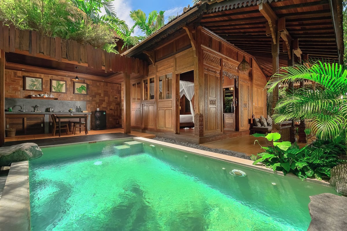 Uma área à beira da piscina com uma estrutura de madeira, um espaço de refeições e um quarto com cama de dossel.