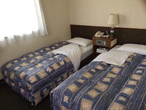Une chambre d’hôtel avec deux lits, chacun agrémenté d’une literie à motifs, une table de chevet avec une lampe et un téléphone.
