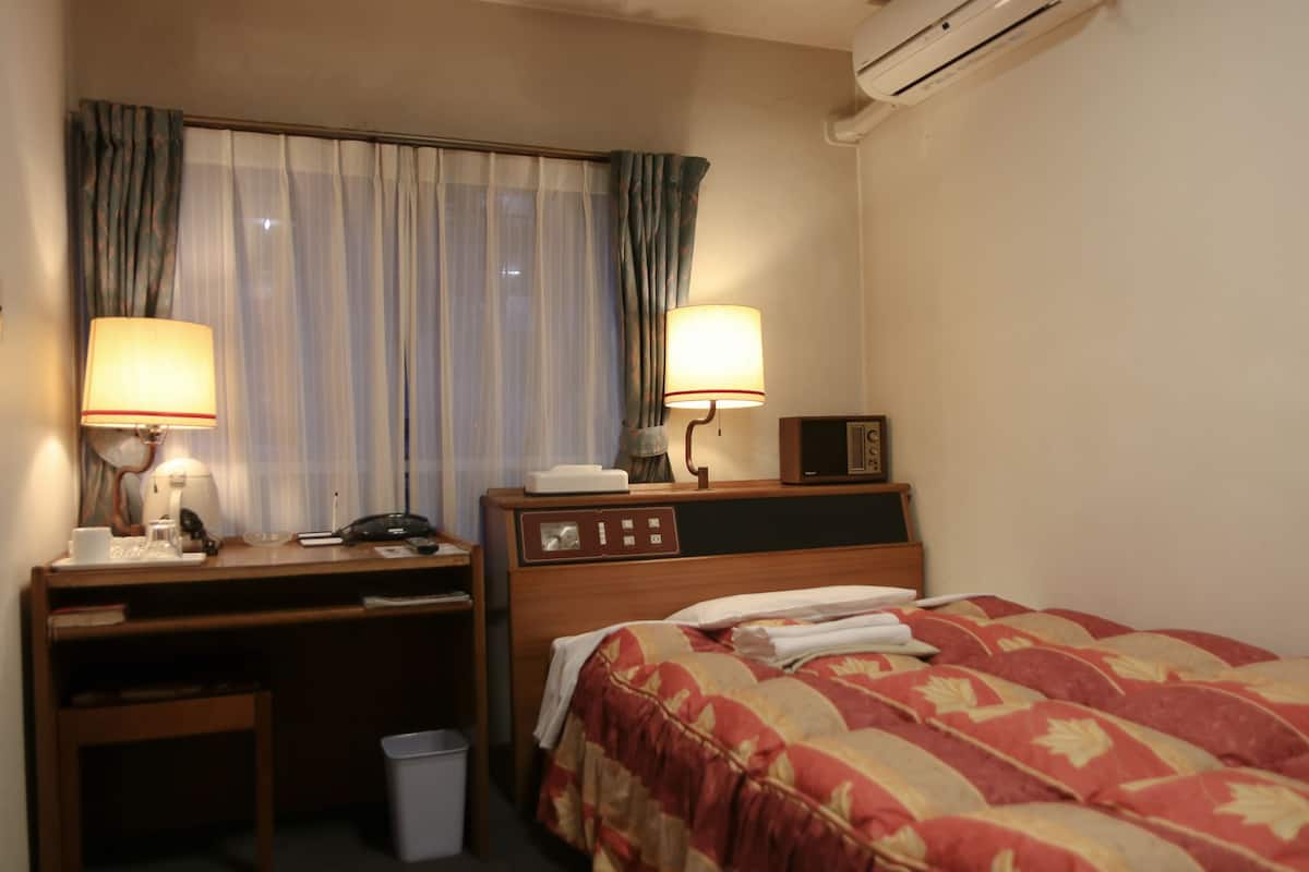 Habitación de hotel con cama, escritorio y dos lámparas.