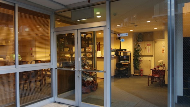 A hotel entrance with a glass door, a reception desk, and a seating area with chairs and a table. - Kochi Business Hotel Bekkan (Kochi)
