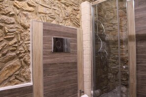 Un área de ducha con un fondo de pared de piedra y un cerramiento de ducha moderno.