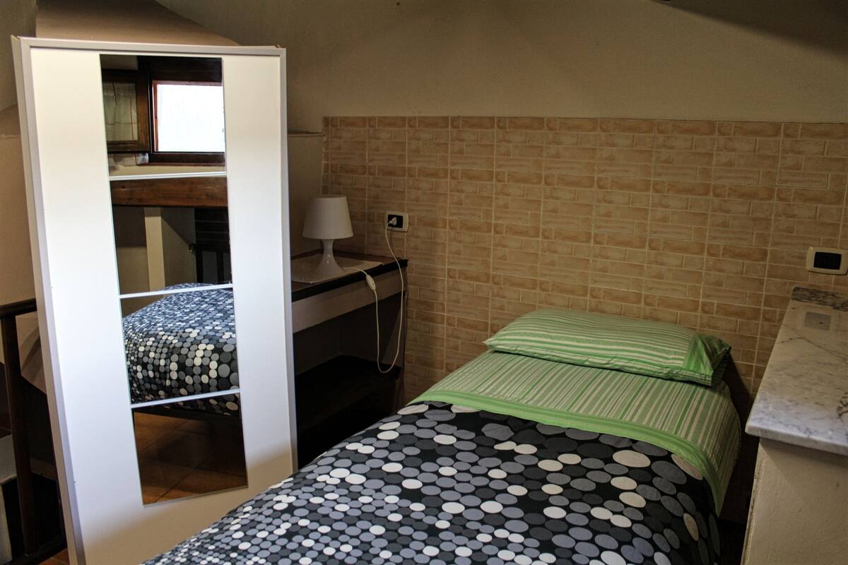 Habitación pequeña con una cama litera, un escritorio con lámpara y una pared con diseño de ladrillos.