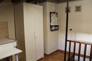 Ein Zimmer mit einem weißen Schrank, einer Pinnwand und einem kleinen Tisch.