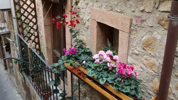 A stone building with a wooden balcony railing, a lattice door, and a window with a wooden frame. - Guest House La Casetta (Piazza Armerina)