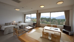 A hotel room with a bed, a desk, a chair, a TV, and large windows offering a mountain view. - Kagetsuen (Hakone)