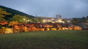 A large building with a flat roof and multiple windows, surrounded by a well-maintained lawn and colorful autumn foliage. - Kagetsuen (Hakone)