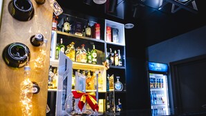 Eine Barbereich mit Regalen voller Spirituosenflaschen, einem Kühlschrank und einem dekorativen Glas mit Schleife.