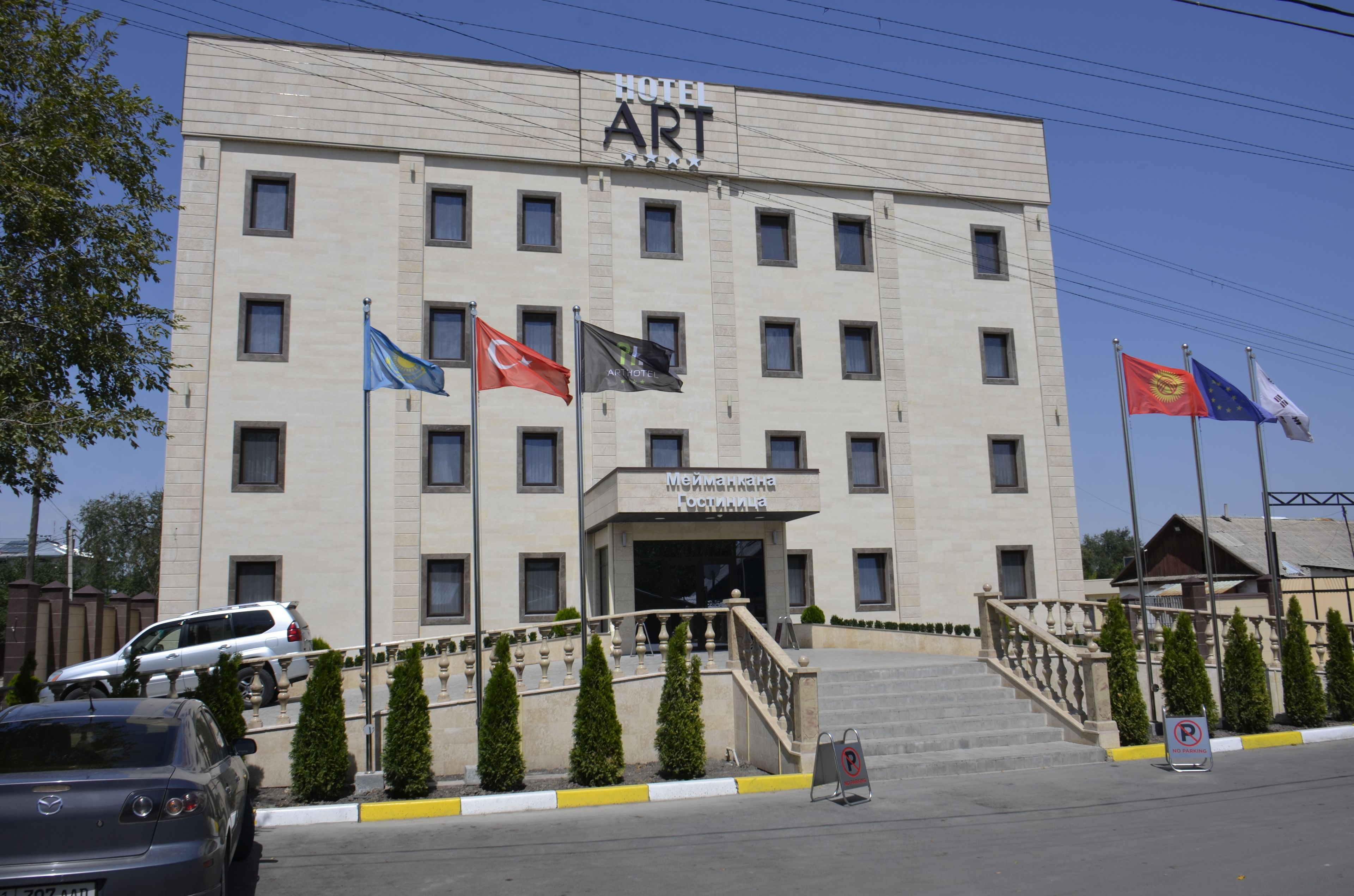 A hotel with a modern facade, multiple flags, and a staircase leading to the entrance.