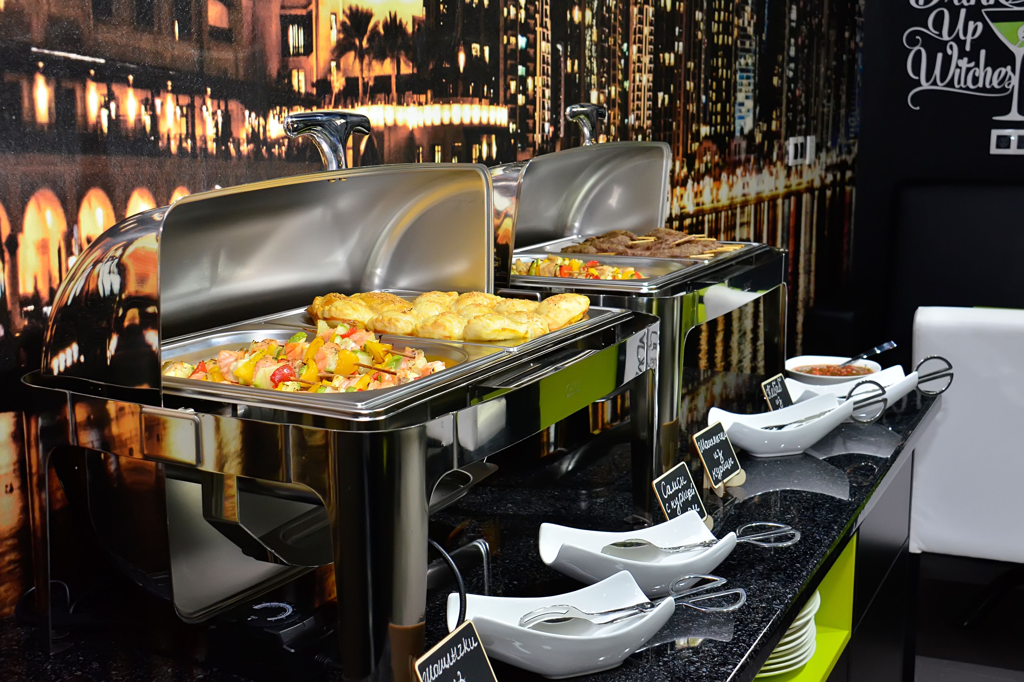 A buffet setup with various food items and utensils.