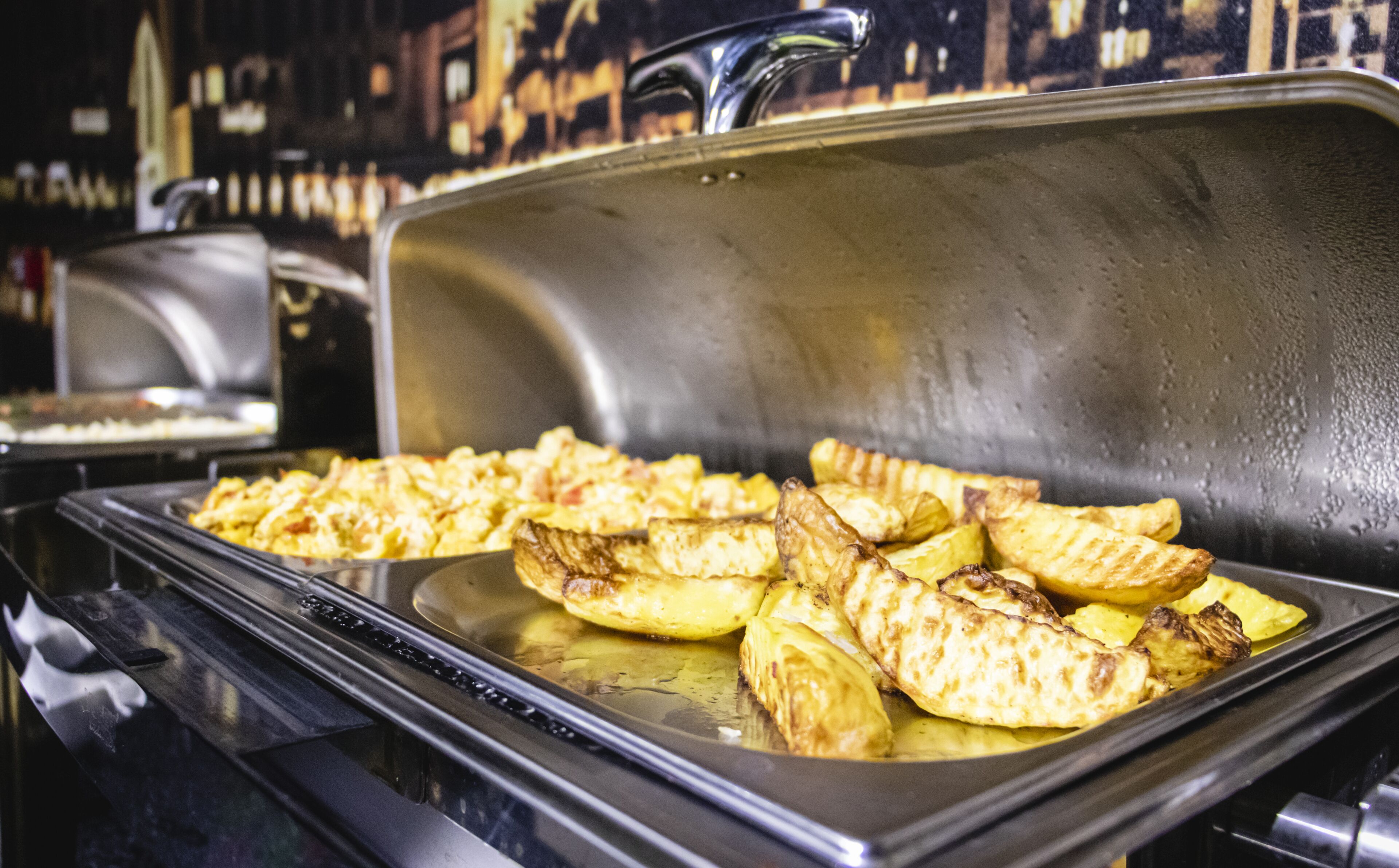 Un bufé con alitas de pollo a la parrilla y papas.