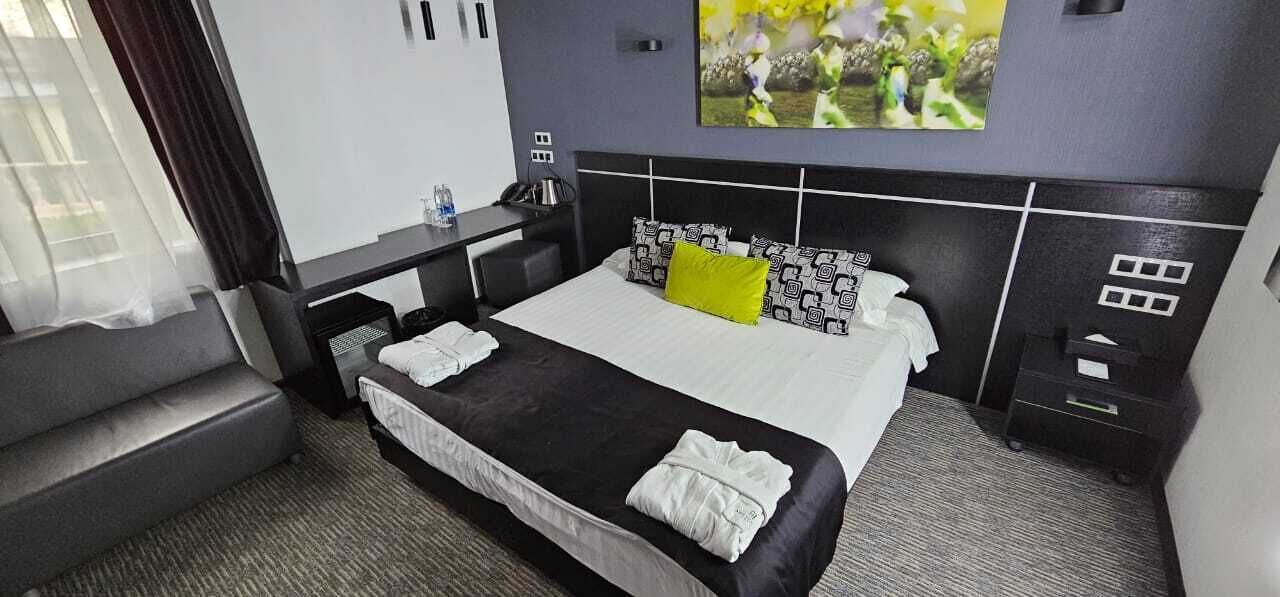 A hotel room with a bed, a desk, a chair, and a TV.
