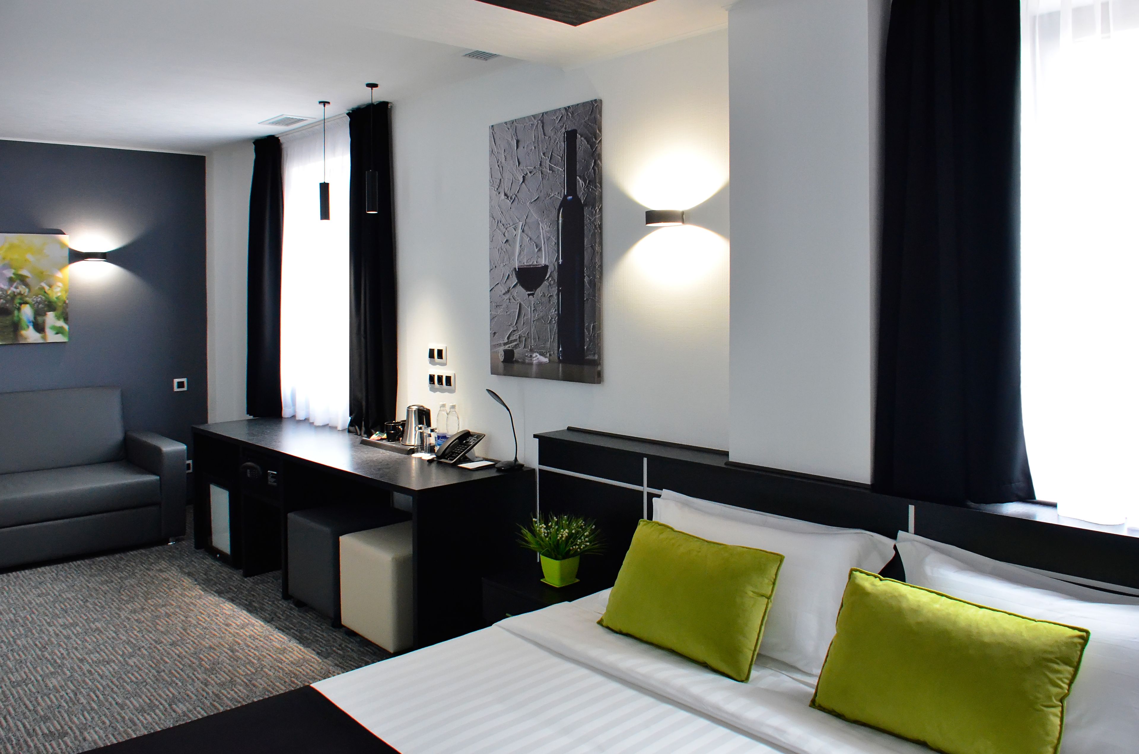 Habitación de hotel moderna con cama, escritorio, sofá y una obra de arte colgada en la pared.