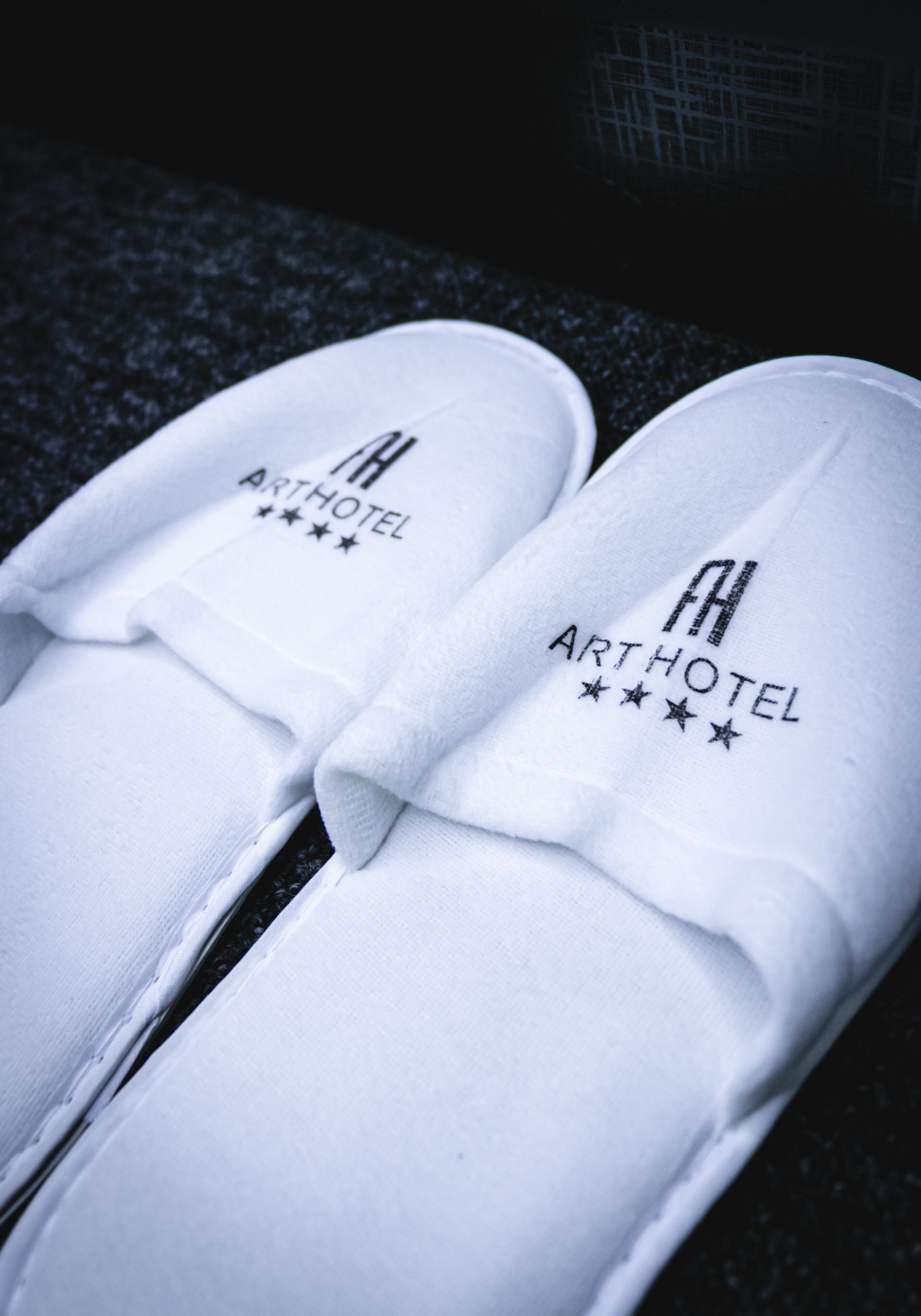 A pair of white slippers with the text "ARTHOTEL" and four stars.