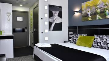 Una habitación de hotel moderna con una cama grande, un escritorio con teléfono y un cuadro en la pared.