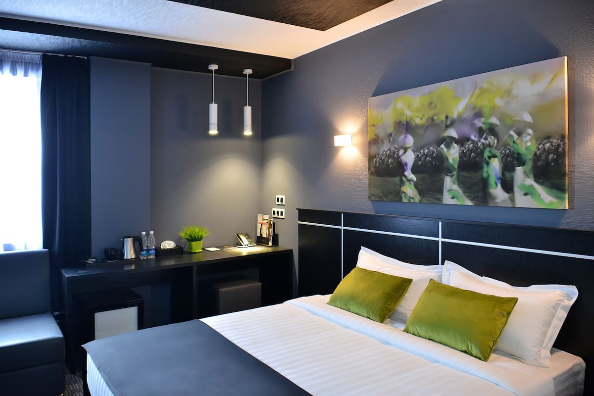 Een moderne hotelkamer met een groot bed, een bureau en een wanddecoratie.
