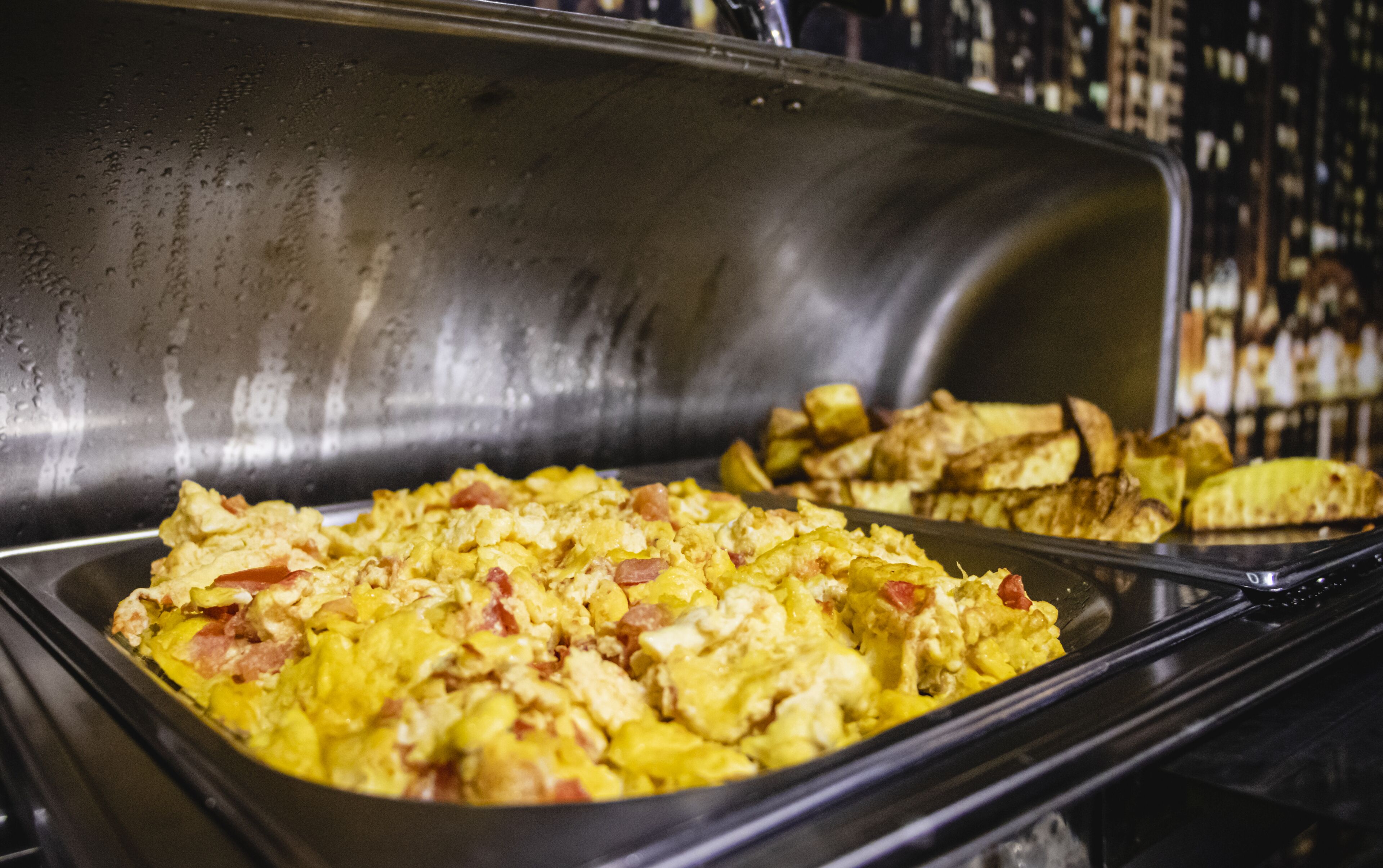 A buffet with scrambled eggs and roasted potatoes.