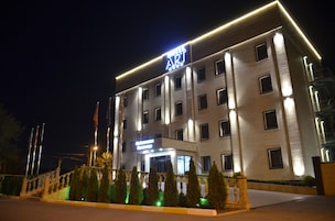 A modern hotel with a prominent sign, multiple windows, and a well-lit entrance.