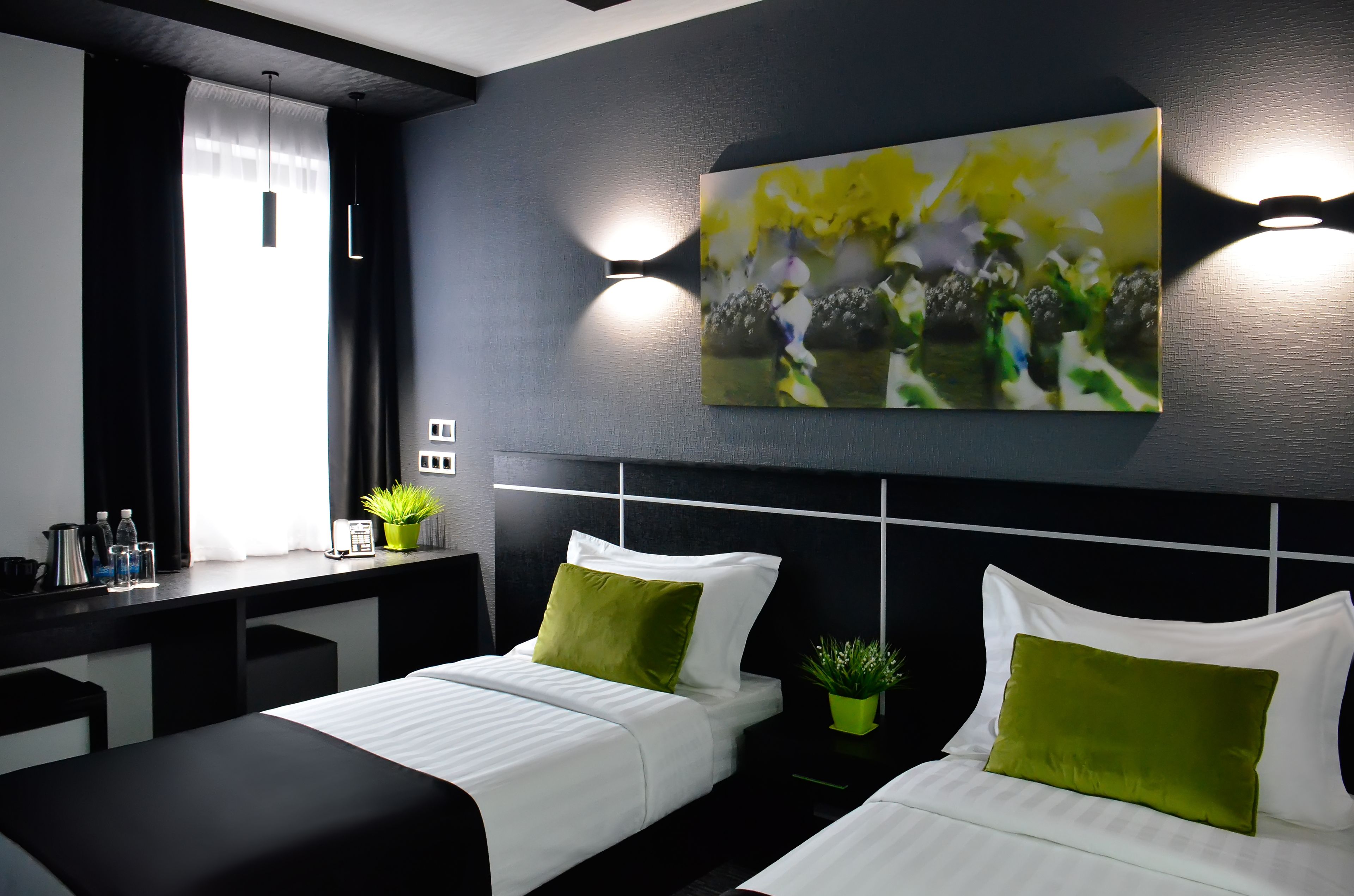 Ein modernes Hotelzimmer mit zwei Betten, einem Schreibtisch und einem großen, abstrakten Gemälde an der Wand.