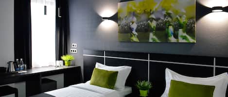 Ein modernes Hotelzimmer mit zwei Betten, einem Schreibtisch und einem großen, abstrakten Gemälde an der Wand.