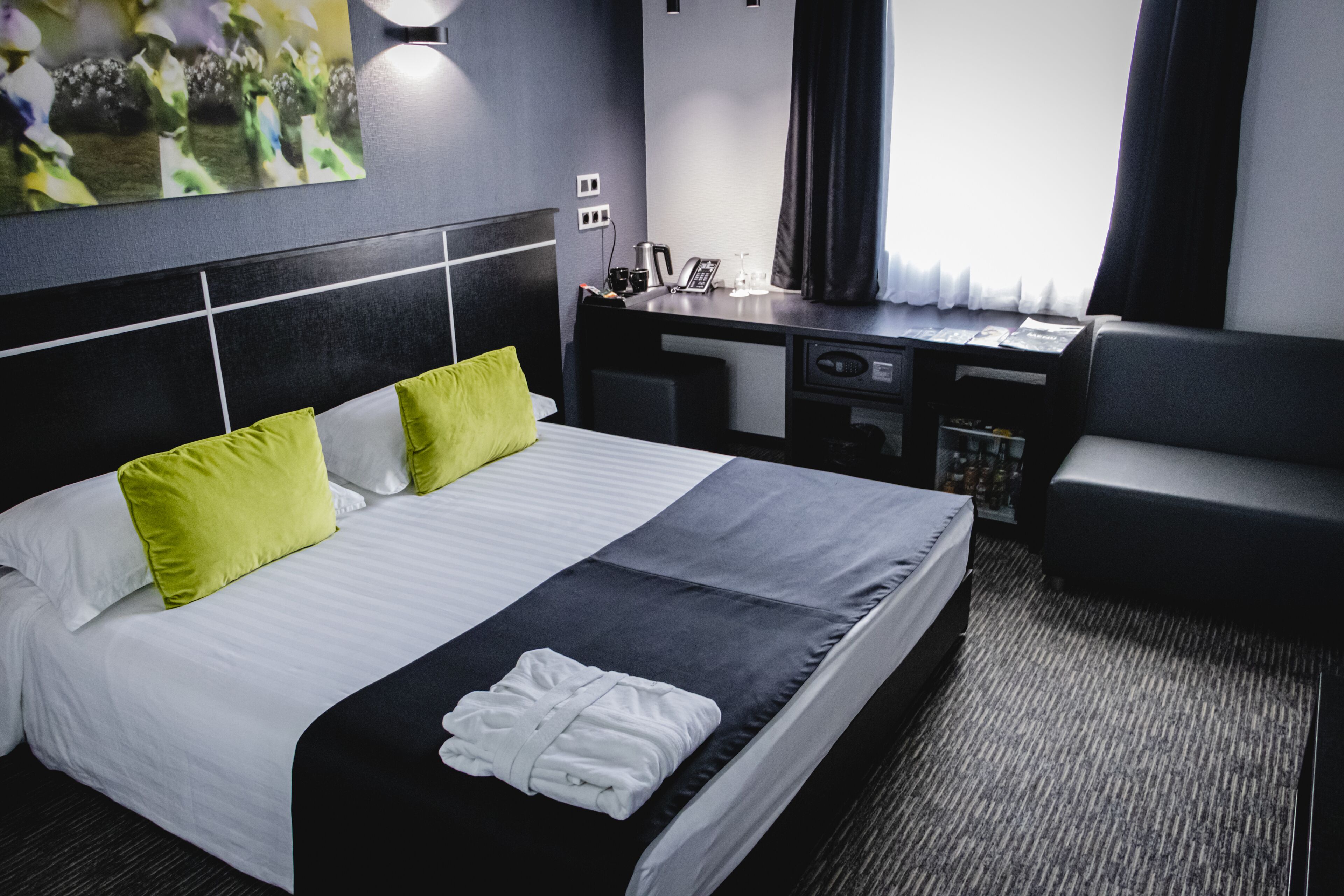 A hotel room with a large bed, a desk, a chair, and a small table.