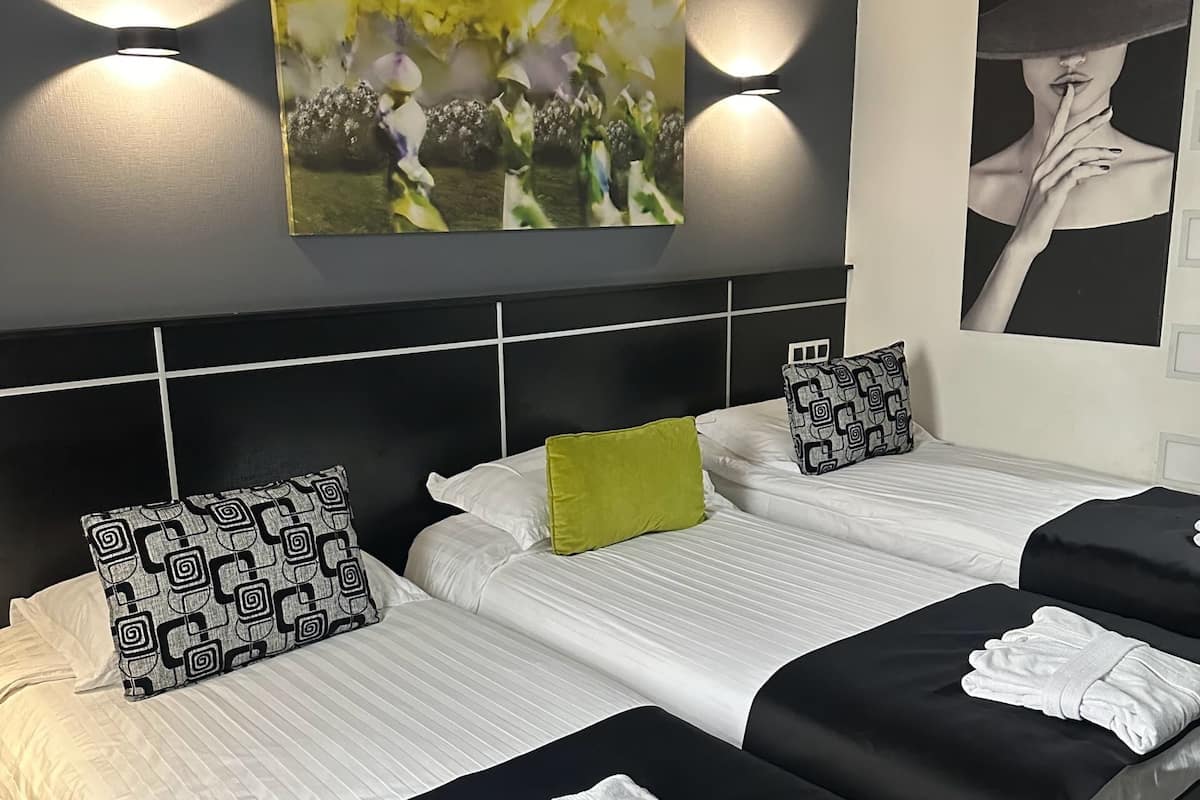 Een hotelkamer met twee bedden, een hoofdeinde, een schilderij en een wandlamp.